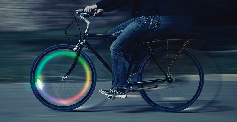 Someone riding a bike with a rainbow glowing front wheel