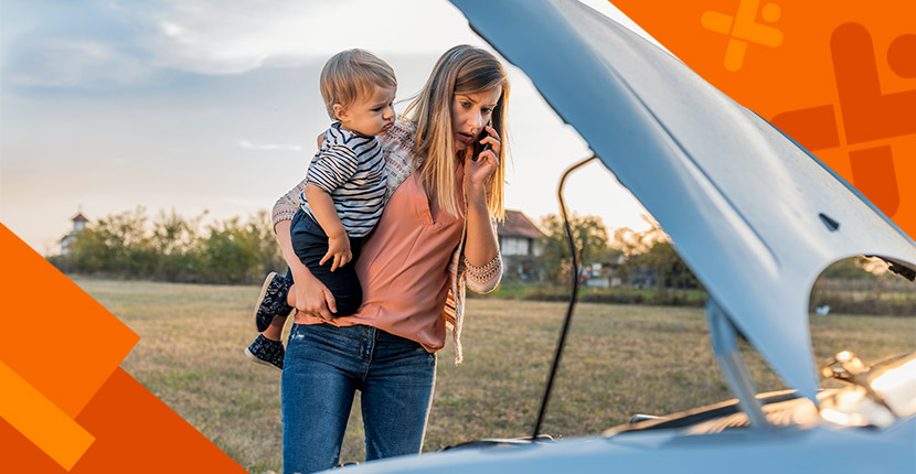 Woman on her phone holding a child looking under the hood