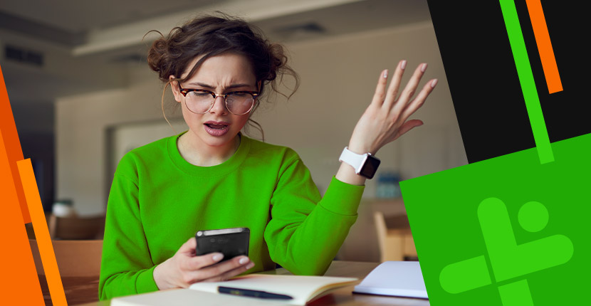 woman in green shirt looking upset at her phone