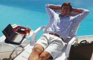Man in a chair on the deck with laptop and cell phone